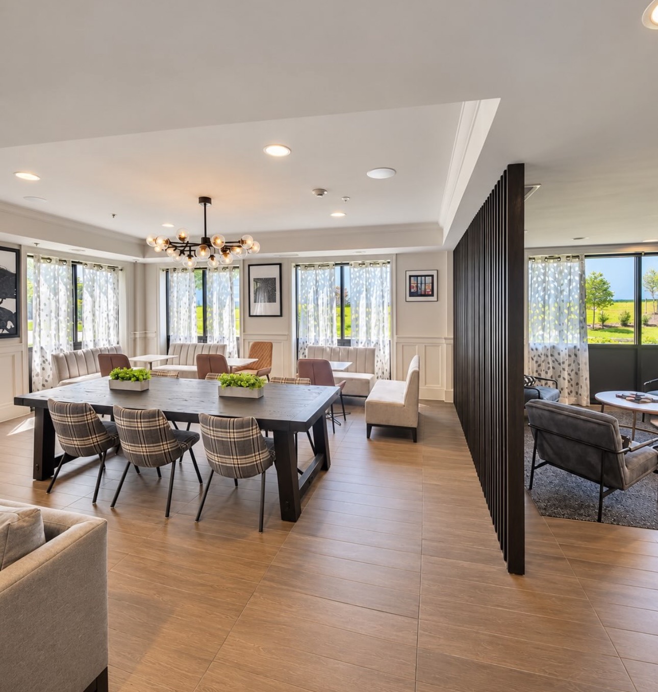 Bright dining and lounge space with wood flooring and a slatted divider